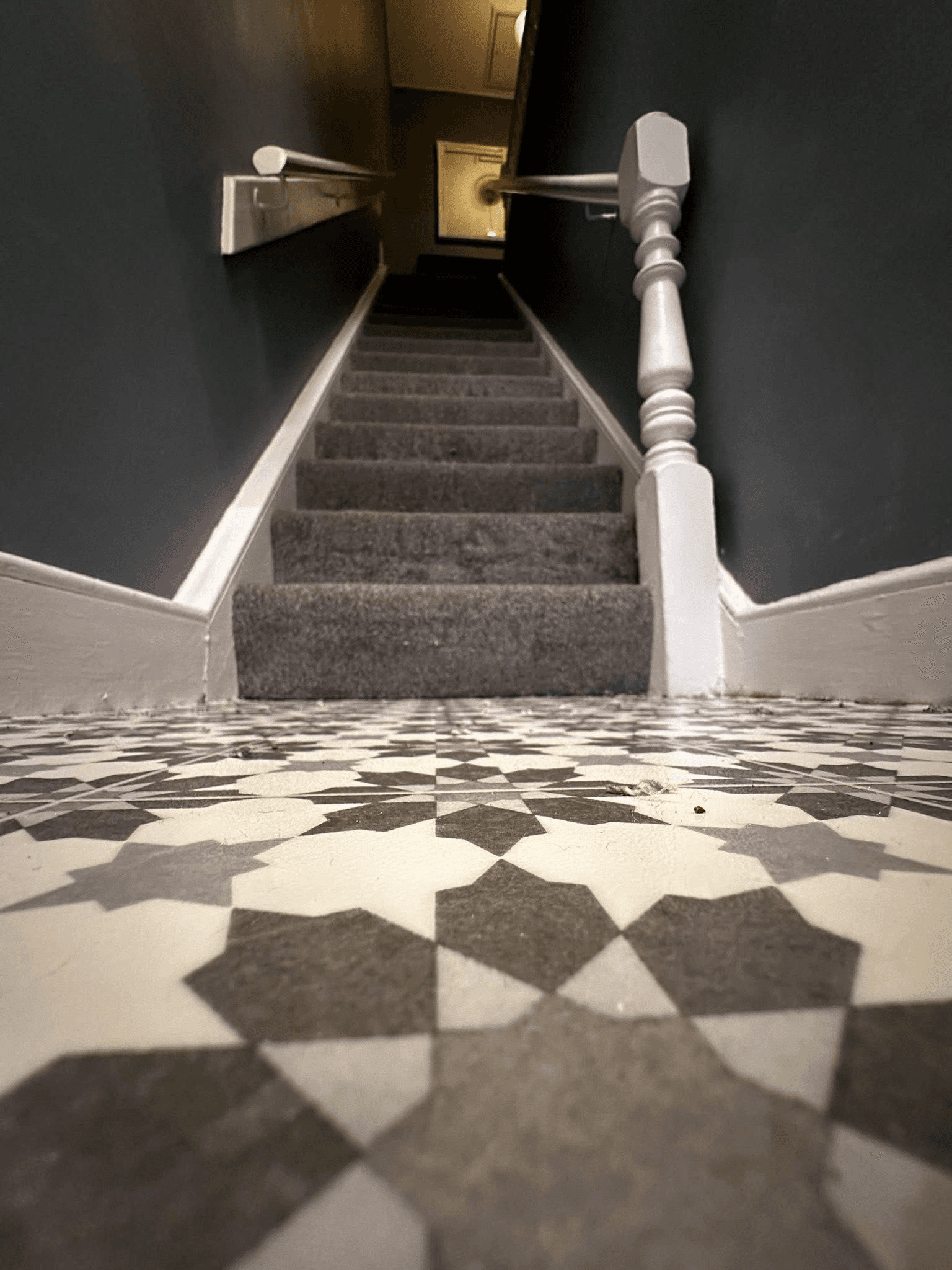 Geometric patterned vinyl in hallway with grey carpet stairs