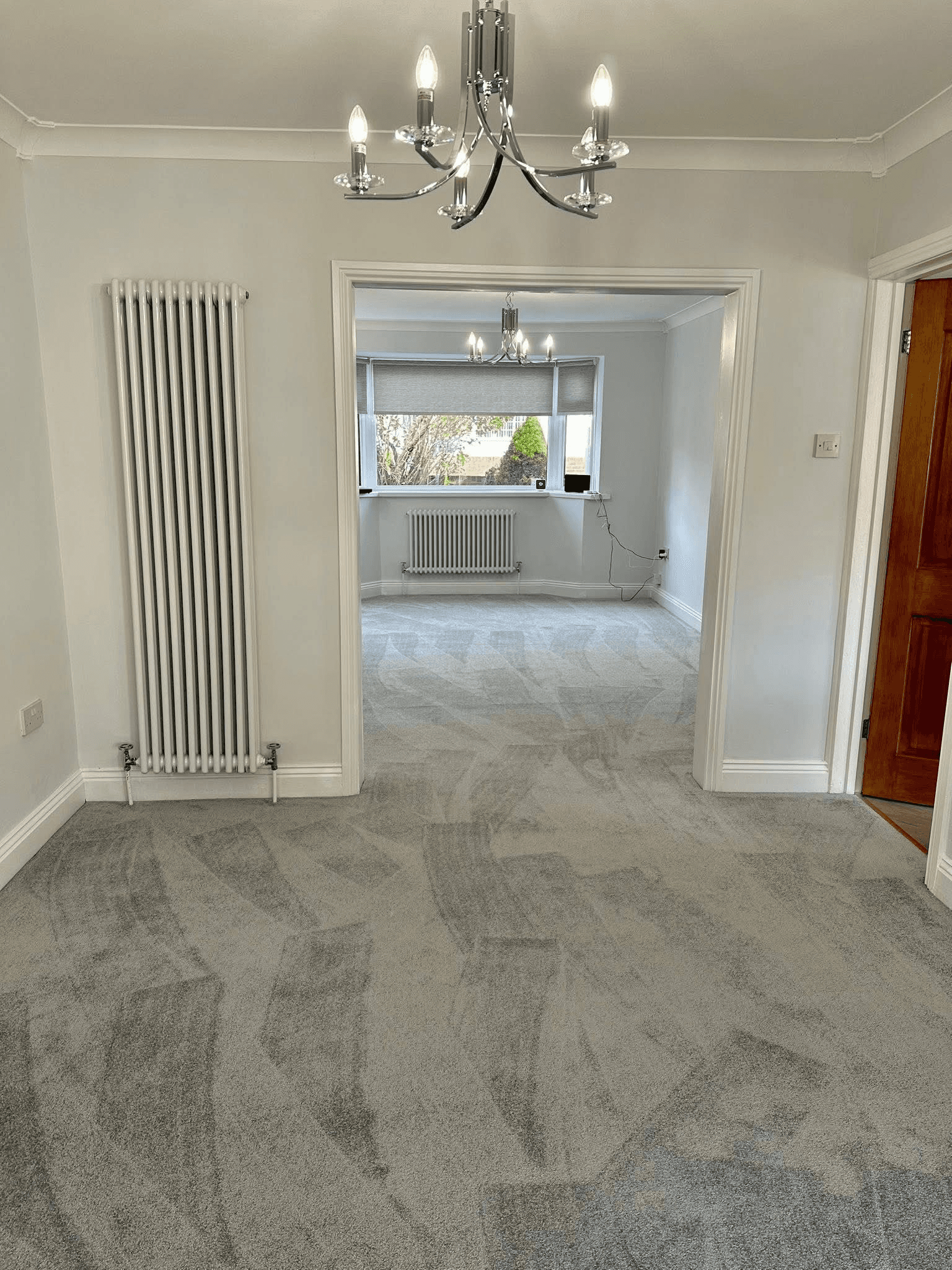 Light grey patterned carpet in bright living room with feature chandelier