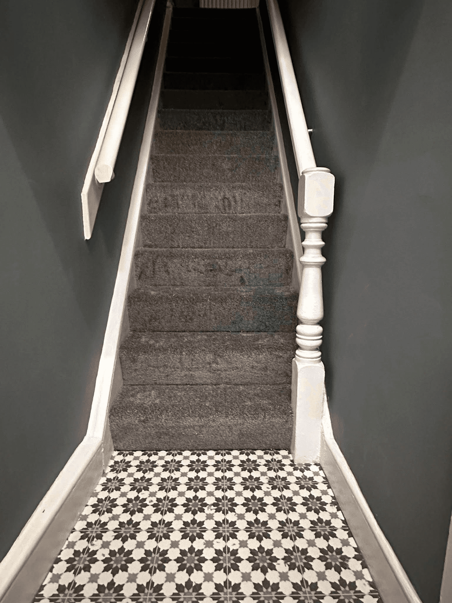 Grey carpet on staircase with geometric vinyl at base of stairs
