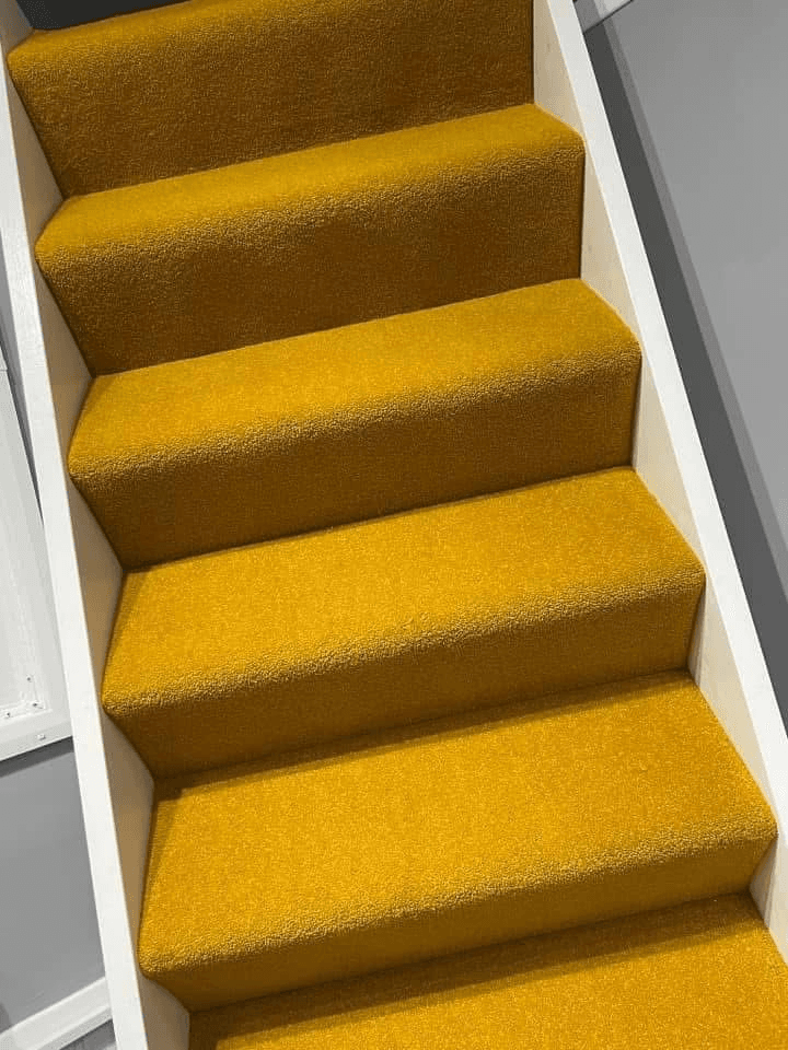 Bold mustard yellow carpet fitted on staircase with white painted surrounds